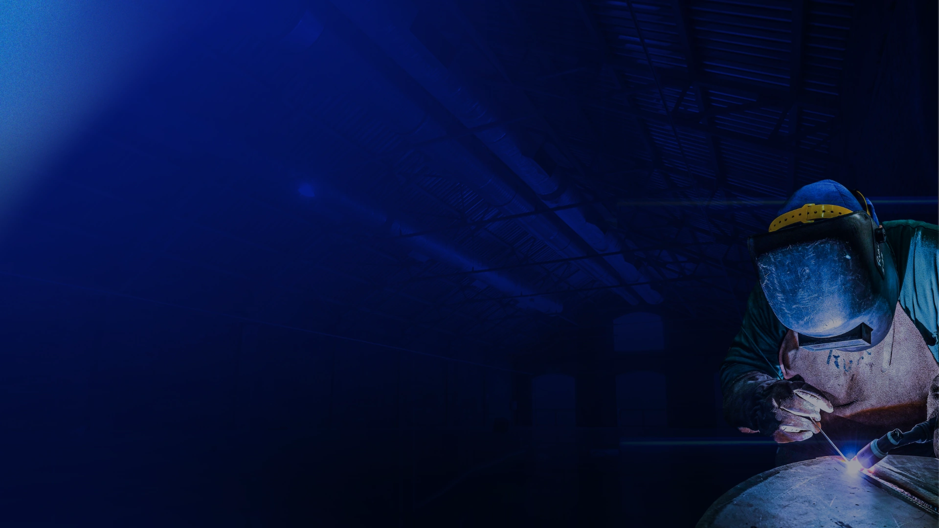 Soldador industrial em operação sob iluminação azul-marinho, capa do estudo Panorama das Vendas Industriais 2026