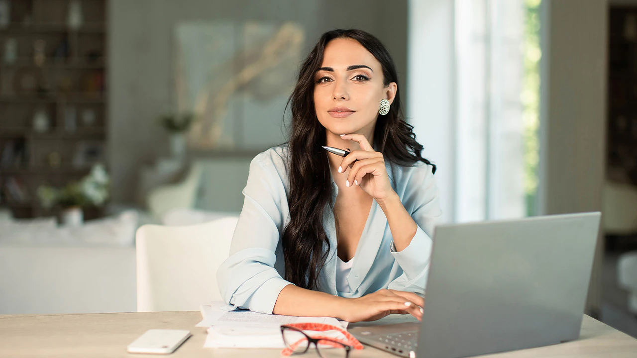 Profissional de vendas sentada à mesa com o notebook aberto, analisando o processo comercial da empresa.